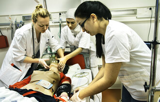 Bilde viser sykepleiere som jobber på en simuleringsdukke.