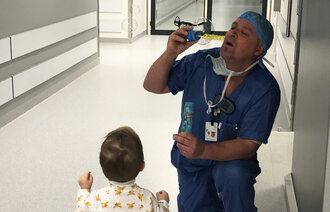 Bildet viser en mannlig sykepleier sammen med et lite barn