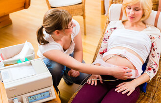 Bildet viser en gravid kvinne som blir undersøkt av jordmor