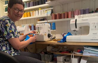Bildet viser sykepleier Katrine Vinje Kleiven som syr Supermann-luer.