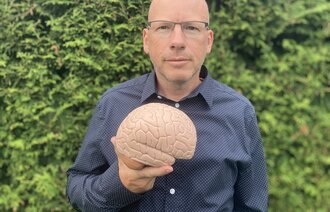 Bildet viser Tommy Skar som viser frem en plastmodell av en hjerne