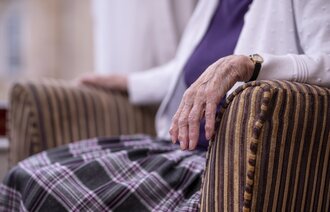 Bildet viser en eldre kvinne som sitter i en stol.