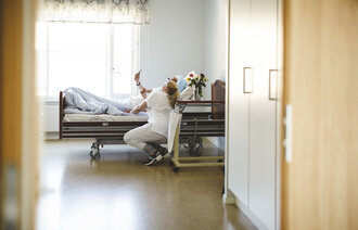 Bildet viser en sykepleier og en pasient som ser på mobilen sammen