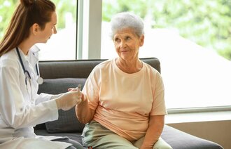 Bildet viser en kvinnelig lege som måler blodsukkeret til en eldre dame