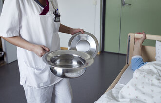 Bildet viser en uidentifiserbar helsefagarbeider som holder et bekken