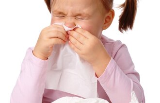 Bildet viser en liten jente som snyter seg