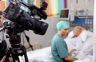 Bildet viser en anestesisykepleier som sitter på sengen med med en dukke som simulerer pasient