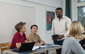 Bildet viser en lærer som diskuterer med tre elever