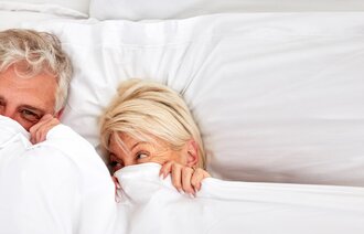 Bildet viser to godt voksne personer som ligger under dyne