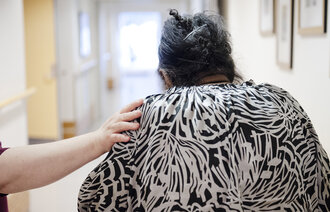 Bildet viser en sykepleier som holder en hånd på skulderen til en kvinne.