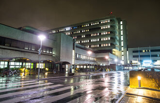 Bildet viser Stavanger universitetssjukehus (SUS) fra veistubben inn mot hovedinngangen i mørket.