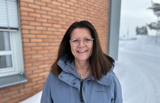 Bildet viser Torhild Sørum. Det er vinter. Hun har på seg en blå jakke og hun smiler til kameraet.