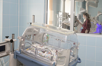 Bildet viser et nyfødt barn som ligger i en inkubator