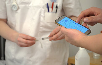 Bildet viser en hånd som holder i en mobiltelefon.