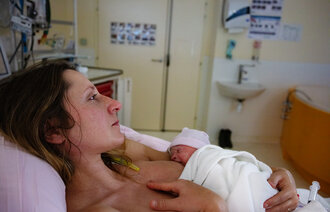 Bildet viser en kvinne som har nettopp har født, og som ligger med den nyfødte på brystet.