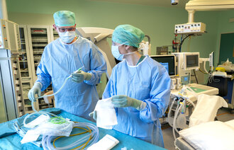 Bildet viser en kirurg og en sykepleier som forbereder medisinsk utstyr før en operasjon.