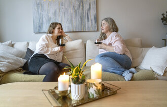 Bildet viser to kvinner som drikker vin i sofaen.