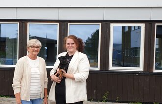 Bildet viser enhetsleder Åse Kalvik som har hundevalpen Frøya på armen, og personalsjefen, Helen Skogan,