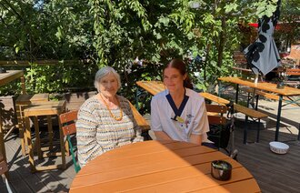 Sykepleier og beboer sitter i Biergarten