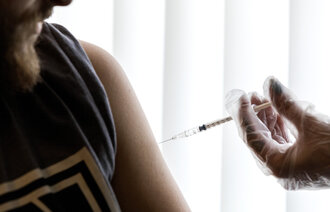 Bildet viser en mann som får en sprøyte med vaksine