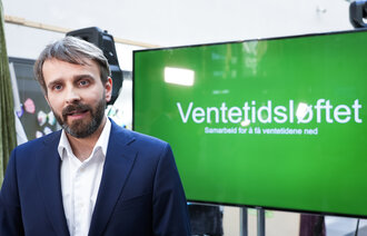 Bildet viser helseminister Jan Christian Vestre foran en skjerm som det står "ventetidsløftet" på.