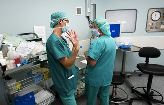 Bildet viser to sykepleiere i dialog på en operasjonsstue.