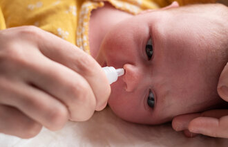 Bildet viser en baby som får nesedråper.