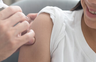 Bildet viser en ung jente som får vaksine i overarmen