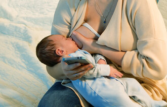 barn som ammes mens mor leser på mobil