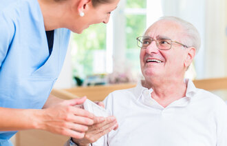 Bildet viser en sykepleier som gir medisiner til en eldre pasient