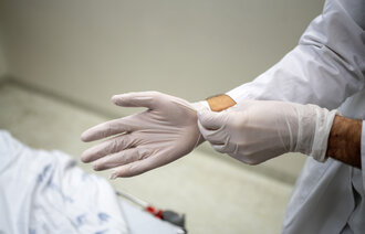 Bilde av helsepersonell som tar på seg hansker