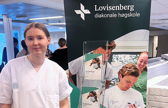 Bildet viser sykepleierstudent Stella Braathen-Reif på et arrangement. Hun står foran standen til Lovisenberg diakonale høgskole