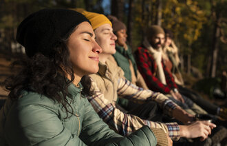 Bildet viser flere mennesker som sitter ute og nyter naturen i stillhet.