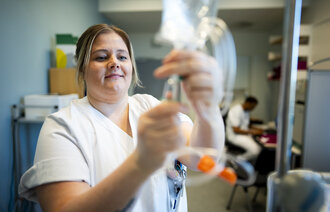 Bilde viser spesialsykepleier Lena Trogstad Risvik som åpner en intravenøspose.