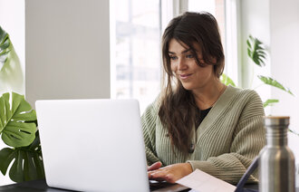 Bildet viser en student som sitter på laptopen sin hjemme