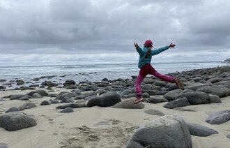 Bildet viser et barn som hopper fra stein til stein på en strand