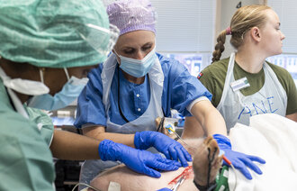 Bildet viser Mona Karine Soli-Andersen som trener på å blottlegge vene på halsen til en gris.