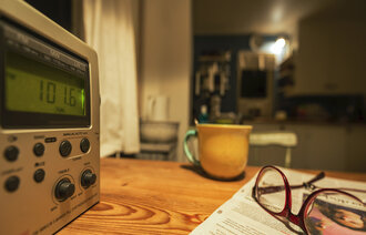 Bildet viser radio, kopp og briller på bord. Illustrasjonsfoto.