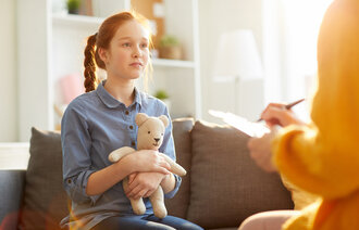 Bildet viser en trist jente som snakker med en helsesykepleier