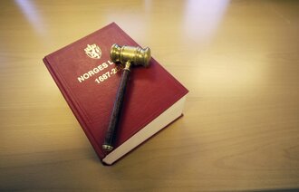 Bildet viser en klubbe som ligger oppå Norges lover