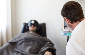 Bildet viser en pasient i en stol og behandleren i forgrunnen