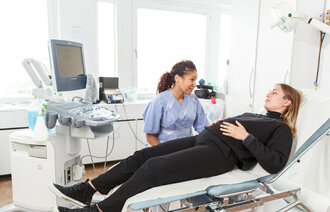 bildet viser en jordmor på jobb med gravid kvinne