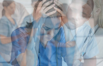 The photo shows a montage of various nurses. A woman in front of the photo is holding her hands on her heads. She seems to be in despair.
