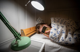 bilde av kvinne i sengen med mobil