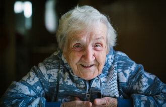 Bildet viser en eldre, smilende kvinne