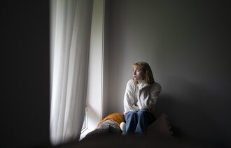 Bildet viser en kvinne som sitter ved et vindu.