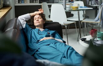 Bildet viser en sykepleier som er utslitt og trøtt