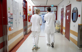 Bildet viser helsepersonell som går i en gang.