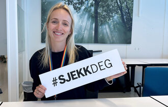 Bilde viser Elin Englund Ørum, med en plakat som sier #sjekkDEG