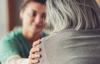 Bildet viser en sykepleier som trøst en eldre pasient med demens